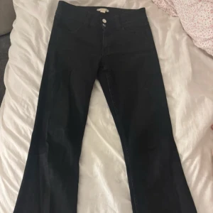 Svarta bootcut jeans Gina Tricot 158 - Svarta jeans från Gina Tricot i storlek 158. Modellen har bootcut-ben och klassisk femficksdesign med broderade bakfickor. Jeansen är i stretchigt denimtyg och har hög midja för en snygg siluett.