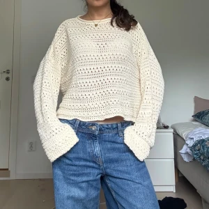 Beige stickad tröja med vida ärmar - Säljer en beige stickad tröja med hålmönster och vida, långa ärmar. Tröjan har en avslappnad, loose passform och är något croppad. .