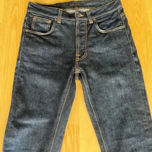 Mörkblå jeans från Nudie Jeans - Snygga mörkblå jeans från Nudie Jeans med klassisk femficksdesign och kontrastsömmar. Säljer då de är för små, priset ej hugget i sten!