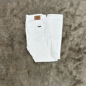 Vita jeans från Nudie Jeans - Snygga vita jeans från Nudie Jeans i modellen skinny fit. Byxorna har klassisk femficksdesign, diskreta slitningar framtill och läderpatch med logga bak. Tillverkade i mjuk bomull med stretch för extra komfort.