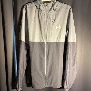 Under Armour Windbreaker - Tja, säljer en grå eftertraktad Under Armour Windbreaker. Skick 10/10, knappt använd. Storlek M. Nypris 1300, mitt pris 549 men kan diskuteras vid intresse. Hör av dig vid frågor o funderingar!