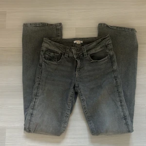 Grå jeans från Gina Tricot, storlek 164 - Snygga grå jeans från Gina Tricot i storlek 164. Klassisk femficksmodell med raka ben och silverfärgade knappar på bakfickorna. Jeansen har bälteshällor och är tillverkade i mjukt denimtyg. Perfekta för en avslappnad och cool look.