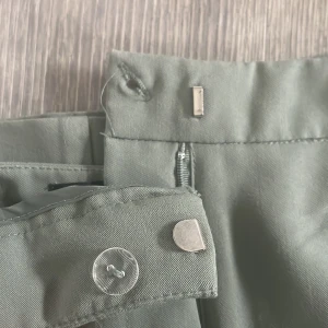 Gröna kostymbyxor med raka ben - Så snygga ljusgröna kostymbyxor med raka ben. Byxorna har dold dragkedja och bälteshällor. Materialet känns mjukt och har en lätt glans. 