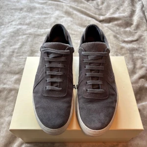 Grå sneakers från Axel Arigato mocka - Snygga grå sneakers från Axel Arigato i mjuk mocka och vit platt sula. 