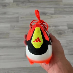 Adidas Predator elite fotbollsskor svart/röd - Säljer ett par Adidas Predator elite fotbollsskor med svart ovandel, vita detaljer och röda snören. Skorna har en syntetisk Hybridtouch 2.0-överdel, orangefärgade dobbar och gula detaljer vid hälen. Perfekta för dig som vill sticka ut på planen.