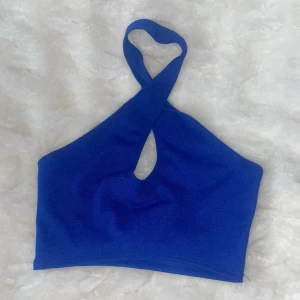 Blå topp med twistad hals - Snygg blå topp med twistad halterneck och en liten cut-out framtill. Modellen är enkel men trendig💙