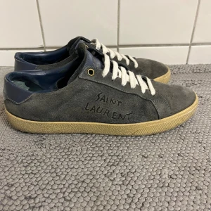 Saint Laurent grå mocka sneakers - Jag säljer dessa saint Laurent skor eftersom dem växt ur mig. Det är storlek 38 men passar 38,5. Skick 8,5/10 . Skorna är såklart äkta. Priset är inte hugget i sten. Hör av er vid frågor✅
