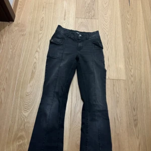 Svarta boot cut jeans från Lindex  - Svarta cargobyxor från Lindex. Byxorna har stora fickor på sidorna har dock inga fickor bak. Materialet är mjukt och stretchigt.