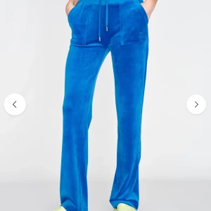 Blå velourbyxor Juicy Couture - Blåa mjukisbyxor från Juicy Couture i mjuk velour med raka ben, snörning i midjan och stora fickor fram och bak. Liten broderad JC-logga framtill. Säljer då dom inte kommer till användning 