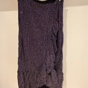 Glittrig svart kjol Gina Tricot - Säljer en svart glittrig kjol från Gina Tricot i storlek S. Klänningen har en snygg rynkad detalj framtill och är tillverkad i ett stretchigt syntetmaterial som glittrar i ljuset. Perfekt för dig som vill sticka ut med en cool look.