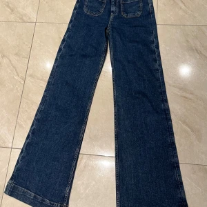 Mörkblå wide jeans med fickor - Snygga mörkblå jeans med breda ben och stora bakfickor. Klassisk denimlook med raka sömmar och en avslappnad passform. Perfekta för dig som gillar en trendig och bekväm stil. Användes 1 gång 