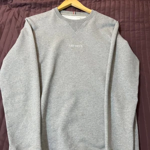 Grå sweatshirt från Les Deux XS - Säljer en stilren grå sweatshirt från Les Deux i storlek XS. Tröjan har rund halsringning med ribbade detaljer och diskret broderad logga på bröstet. Perfekt för dig som gillar enkel och clean stil. Hör av dig om du vill ha fler bilder eller har frågor. 
