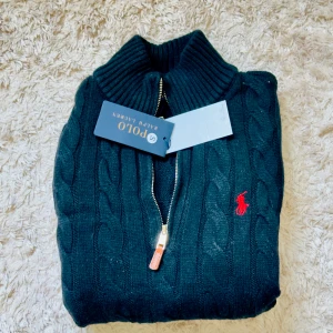 NY Ralph Lauren Cable-Knit Tröja Mörkblå | Storlek S | - Slå till nu och spara stort! Denna helt nya och oanvända Ralph Lauren Cable-Knit tröja i supermjuk bomull är en investering för många säsonger.  ✨ Varför köpa den här av mig för 1000 kr?  · Sparar dig 1300+ kr: Jämför med butikspris på 2300 kr. · Helt ny & oanvänd: Fortfarande i original skick, precis som i butiken. · Exklusiv design: Eftertraktad quarter-zip modell med cable-knit mönster.