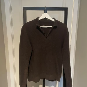 Brun stickad half zip från These Glory Days - Mörkbrun stickad tröja från These Glory Days i storlek S. Tröjan har en snygg half zip-dragkedja vid kragen och är långärmad. Perfekt för lager-på-lager under hösten och vintern. Enkel och stilren design som funkar till det mesta.