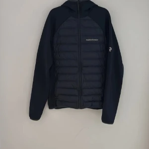 Mörkblå pufferjacka Peak Performance M - Säljer en mörkblå pufferjacka från Peak Performance i storlek M. Jackan har huva, hel dragkedja och quiltad framsida med snygga paneler. Materialet är polyester och jackan har långärmade ärmar. Perfekt för hösten som kommer. Står emot kyla och vind väldigt bra. Använd en säsong och är 10/10 skick. Hör av dig vid intresse och pris kan diskuteras. Nypris: 2700kr