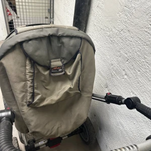 Barnvagn - X-Lander', modell 'X-Lander XQ'. Vagnen har robusta hjul och slitstark klädsel i grönt och gult