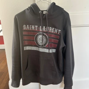 Mörkgrå Saint Laurent hoodie - Säljer nu min snygga hoodie ifrån Saint Laurent, tröjan är i mycket bra skick! Jag säljer den för att den är lite för liten. Tröjan passar dig som är runt 170-180 Storlek : S. Hör av dig vid minsta fundering! 
