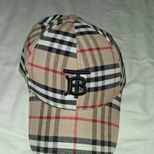 Rutig keps från Burberry - Snygg keps från Burberry keps som är beige. perfekt om man ska ut på sommaren eller ba känna sig snygg. man kan sänka priset om det behövs.. OBS kan bara köpas i väVästerås och så är den inte äkta..