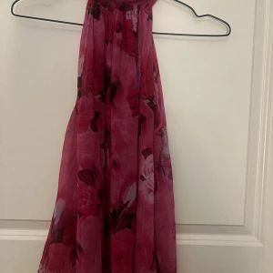 Blommig topp från Mango - Säljer en festlig topp från MANGO. Som är rosa med blommigt mönster, som är halterneck. Tyget är lätt, perfekt för sommarens eller som fest topp. Supersnygg knappt använd!!