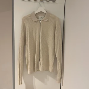 Beige ribbad kofta med dragkedja - Säljer en stilren beige ribbad kofta från jack and jones. Tröjan har lång ärm, klassisk krage och hel dragkedja framtill. Perfekt för lager-på-lager och passar till det mesta. Materialet är mjukt och känns skönt mot huden.