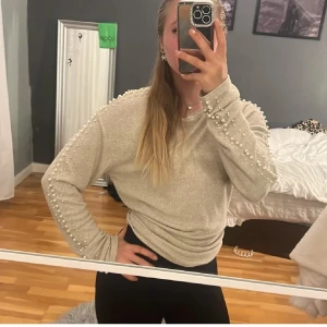 Beige tröja med pärlor från H&M - Superfin beige stickad tröja fràn H&M med linga ärmar och snygga pärldetaljer längs axlar och ärmar. Tröjan är perfekt för skolan, jobb eller vardag. Älskar den säljer pga gör stor för mig.💕✨🍂( Nästan helt oanvänd )