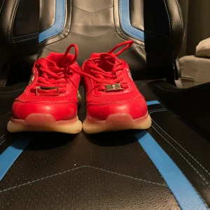 Röda sneakers från Plein Sport - Säljer ett par röda  Phillipe Plein Sport sneakers med chunky vit sula och silvriga detaljer. Skorna har snörning, mesh och skinnpaneler samt logga på sidan. Bak på hälen står det PS 78 i metall. Perfekta för dig som gillar statement-sneakers. Väldigt sköna då perfa för springskor eller ba gå runt i. Nypris 2600