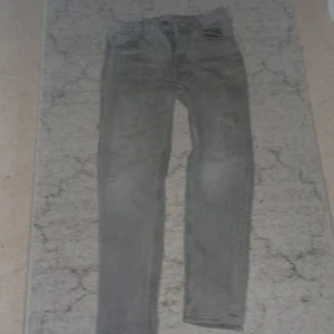 Grå jeansbyxor i rak modell stl 164 - Snygga grå jeansbyxor från C i storlek 164. Klassisk femficksmodell med rak passform och normal midja. Jeansen är tillverkade i ett mjukt bomullstyg med lite stretch för extra komfort. Perfekta för dig som gillar en enkel och stilren look.