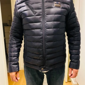 Svart pufferjacka från Morris XL - Säljer en helt ny svart pufferjacka från Morris i storlek XL. Jackan har horisontella quiltade partier, dragkedja framtill och en sned bröstficka med dragkedja. Klassisk Morris-logga på bröstet och stilren design. Perfekt för kyliga dagar. Passar  även en L. 