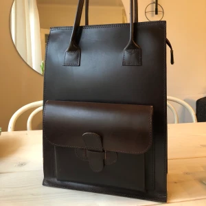 Brun läderväska/kasse från Knulp - Otroligt fin läderväska! Väskan är i nyskick med ett yttre fack samt några små fack på insidan. Passar även för laptop!  Måtten på väskan är L38xB28xD13, längden inklusive handtagen är 61cm.  Kan mötas upp i centrala Stockholm/hämta den hemma hos mig, alternativt skickas och då betalar köparen frakten 💗   