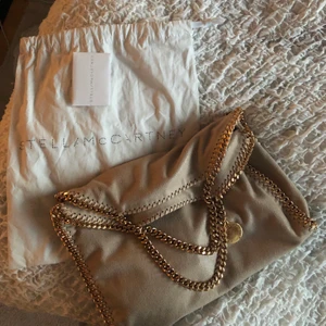 Stella mccartney väska - Så fin  beige Stella mccartney väska med guldiga kedjor, aldrig använd!! Har dustbag och äkthets bevis💕💕 den är väldigt speciell då Stella väskorna ofta har silvriga kedjor. buda från 3000