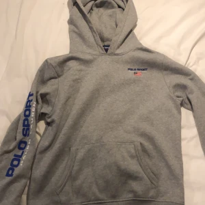Grå Polo Sport hoodie  - Denna hoodien är i mycket fint skick och använd få gånger. Tröjan sitter väldigt skönt och är i bra material. Den är i storlek 18-20 på tröjan men sitter ungefär som 14-16. Tror att den är felmärkt 