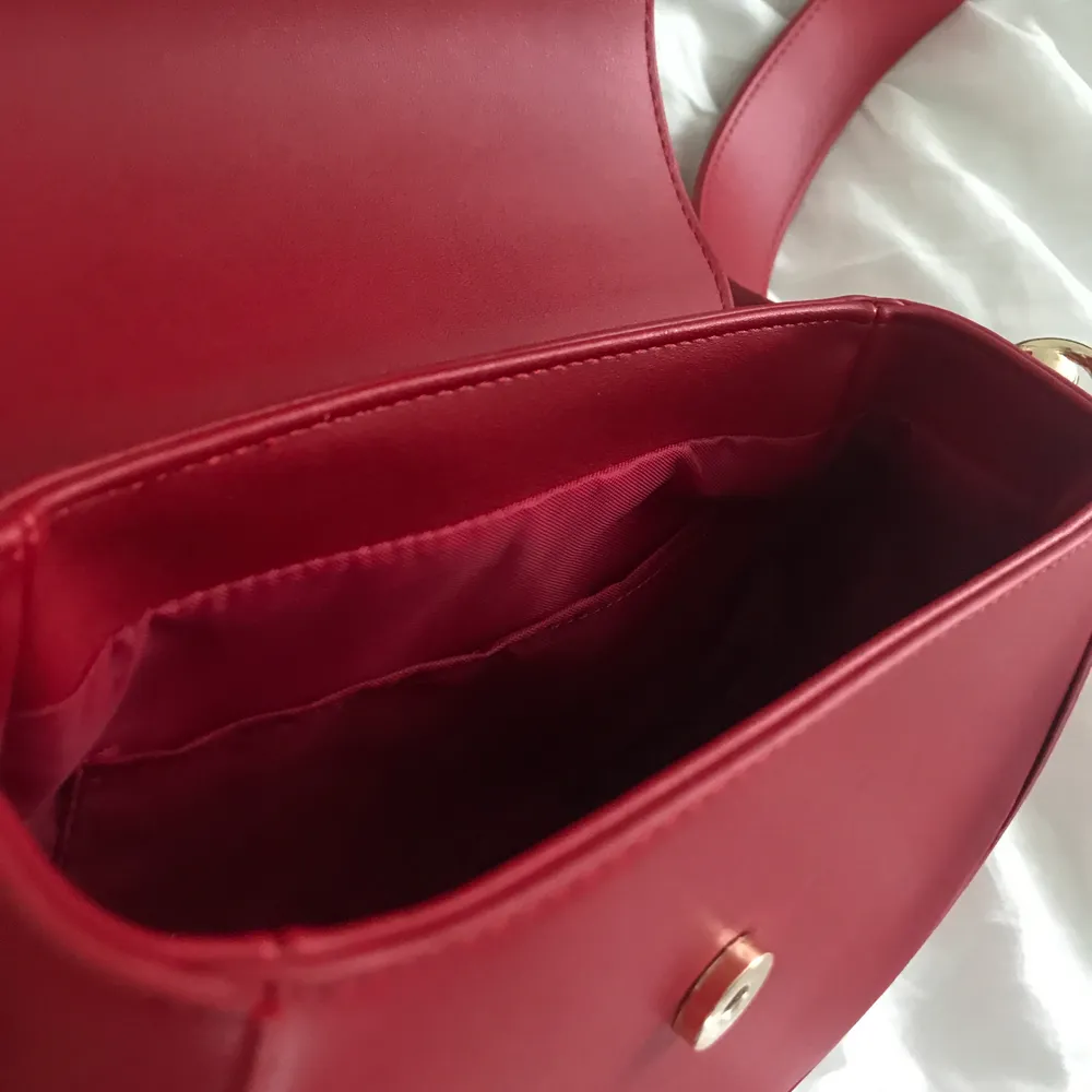 Röd crossbodybag från ASOS! Perfekt storlek som rymmer mycket. En mindre ficka inuti också. . Väskor.