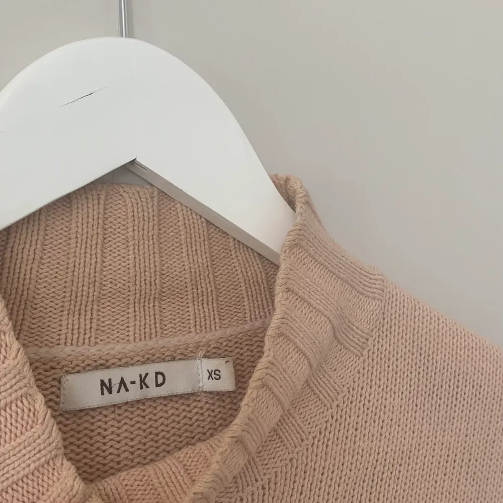 En ljusrosa/ beige stickad polo i bomull som är en sval tröja perfekt att ta på sig på sommaren! Sparsamt använd strl xs från NA-KD. Stickat.