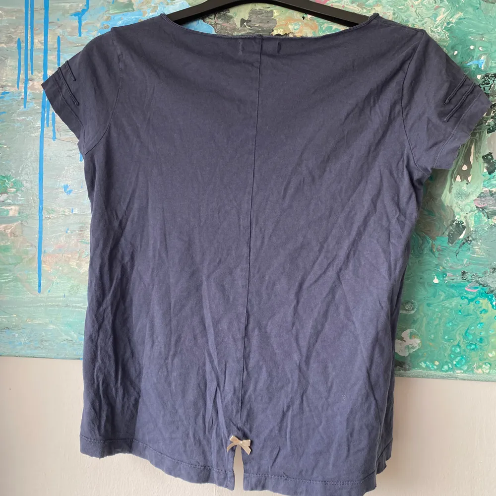 Marinblå T-shirt från märket Odd Molly. Strl 1 eller S. Ficka på framsidan, detaljer vid ärmarna och en slits med rosett där bak. Köpt för ca 4 år sen, använd i början men inte använd på kanske 2 år. Fint skick. . T-shirts.