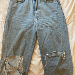 Blåa jeans med hål  - Blåa mom jeans med hål i båda knäna. Byxorna är från H&M och är i storlek 38. Är inte så använda eftersom dom är för stora men väldigt snygga 