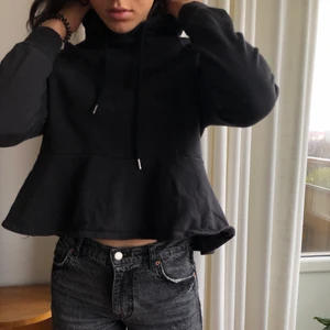 Svart hoodie med volang  - Svart Hoodie med volang detalj och luva. Gråsvart