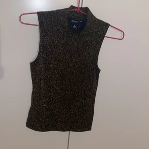 Glittrigt linne  - Svart med guld glitter linne med liten polo krage. Oanvänd då den är för liten för mig. Frakt kan vi dela hälften på. 