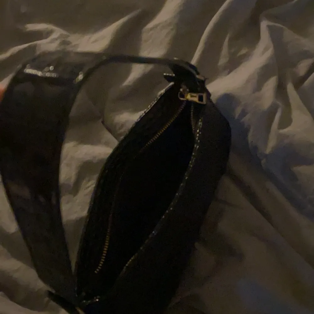 En svart axelremsväska väska med guld detaljer och krokodilmönster. Jätte fin och i bra skick. Köpt för 100kr då jag säljer den för 75kr. Laukut & Käsilaukut.