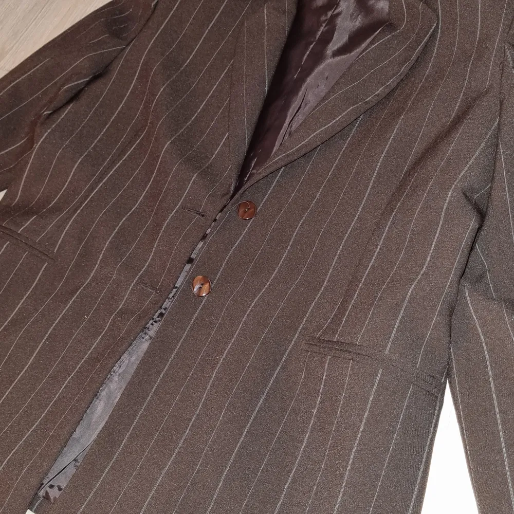 Mörkbrun kavaj med ljusa ränder och bruna knappar. (Frakt får kunden stå för själv om det så önskas). Kostymer.