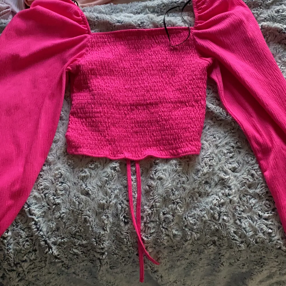 Hot pink lång ärmad tröja croppad men man kan dra åt fram sidan och göra den större och mindre med snörerna . Tröjor & Koftor.