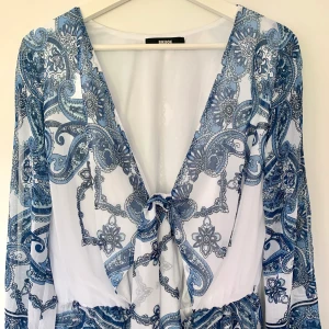 Helt ny shortsdress i stl 38-40/ playsuit - Superfin shortsdress som är helt oanvänd. Säljes då den tyvärr är för liten för mig. Den har resor i midjan samt knytskärp vid bysten. Den har två shortsfickor framtill. Mjukt material närmast huden och ett finare tunnare tyg utanpå. Storlek 38-40.