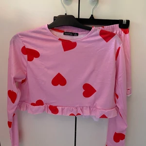 Söt pyjamas med ❤️ - Pyjamas med hjärtan i storlek S💖 crop toppen och shortsen har små volanger. Aldrig använd säljer pga råkat köpa 2 st. Betalning via Swish vid frågor hör av dig 🌼