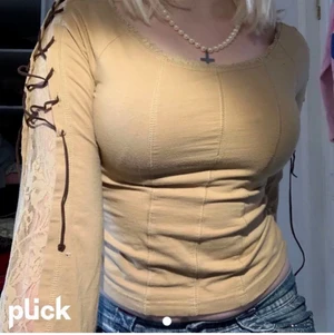 Brun/beige långärmad tröja - Jättefin brun/beige tröja med jättecoola detaljer som spetsöppningen med snören av lädertråd på armen. Även sömmarna på magen är jättefina och ger en korsett känsla. Även spets på flertal ställen
