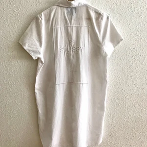 Stüssy vit skjortklänning - Längre kortärmad skjorta/klänning från Stüssy. Köpt för ca 900kr, använd två gånger. Storlek M. Går att fråga efter fler bilder om du är intresserad 🌅
