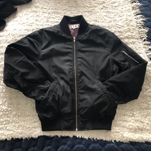 Bomberjacka i storlek 36 - Svart bomberjacka i storlek 36/S. Flitigt använd men i väldigt bra skick. Med resårbandet längst ner, sitter jackan åt längst ner, men pösig upptill. 
