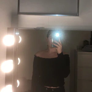 Tröja  - En svart ribbad topp med små volanger längskanterna stl s