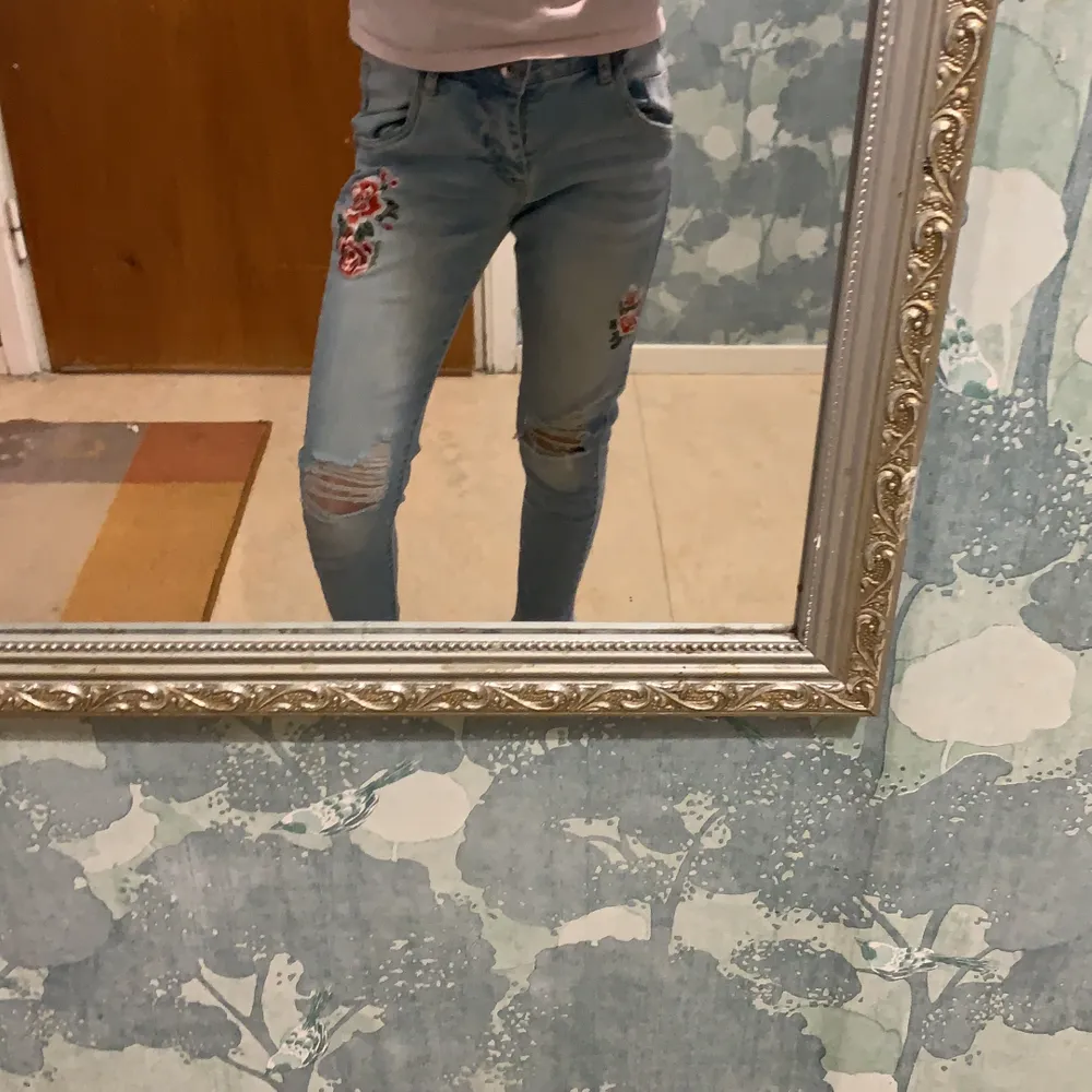 Blå jeans med hål och 2 blommor . Jeans & Byxor.