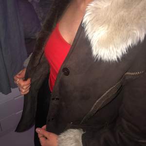 En varm brun lång jacka med fickor och knappar längst fram.