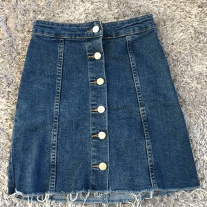 Jeanskjol från Gina Tricot  - Säljer en jättefin jeanskjol från Gina Tricot då den inte passar längre. Den sitter jättesnyggt på och är perfekt till nu till våren och sommaren. Den är insydd där bak till cirka storlek 32, men inget man lägger märke på, se bild 2 & 3. Kontakta mig för mer bilder elle frågor!💌❣️