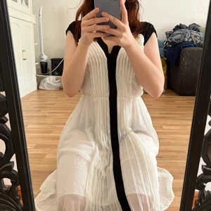 Klänning - Vit klänning med svarta detaljer. Går ungefär till knäna i fram och längre ner i bak!  Storlek 34 :)